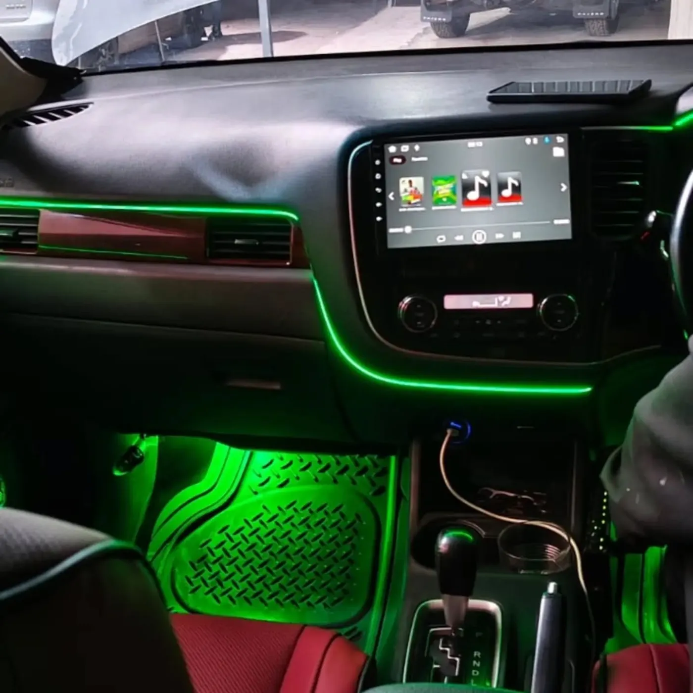 Car interior with green ambient lighting along the dashboard and footwell